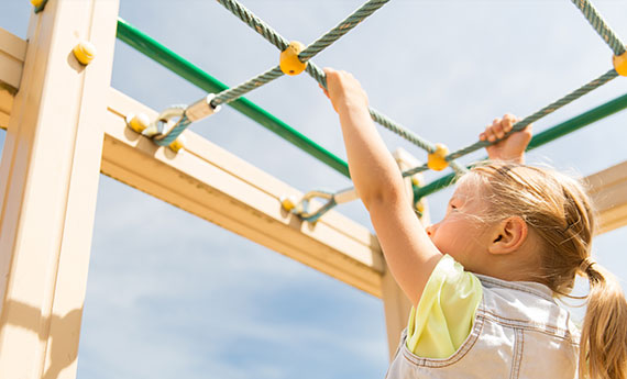 Osmo Anstrich und Farbe – ein Holzgerüst im Garten auf dem ein Kind hangelt und klettert, das Holzgerüst ist mit Osmo Farbe und Anstriche behandelt OSMO