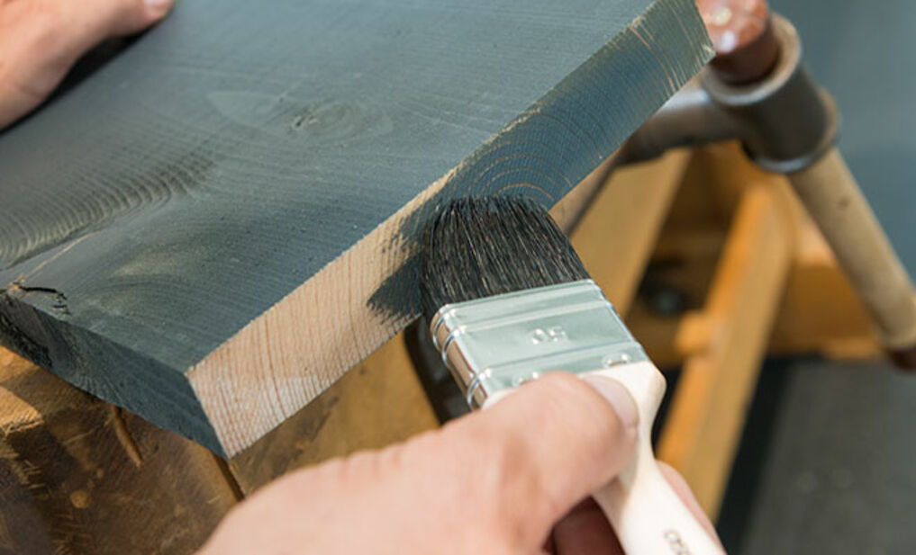 Timber being treated with an oil-and-wax-based Osmo wood coating in transparent grey