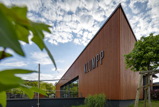 Weingut Klumpp Logo und ihr Gebäude mit der senkrechten Holzfassade in dunkelbraun – Osmo Referenz