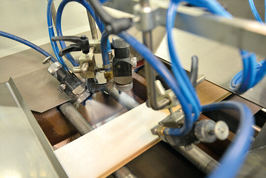 Osmo Maschinen – unsere Spritzlackieranlage beschichtet ein Profilholz mit Osmo Farbe – industrielle Holzbeschichtung