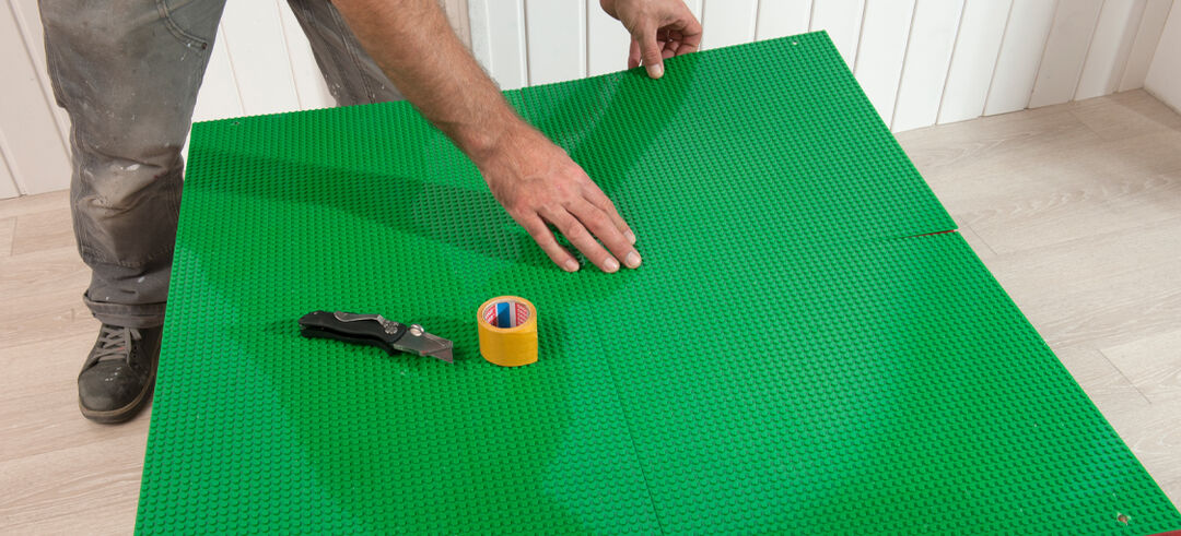 Spieltisch nun gestalten, vier Legoplatten auf die Holzplatte kleben und bündig fixieren für eine große Baufläche. Oder die Oberfläche mit Klebefolien selber bekleben – ganz individuell.