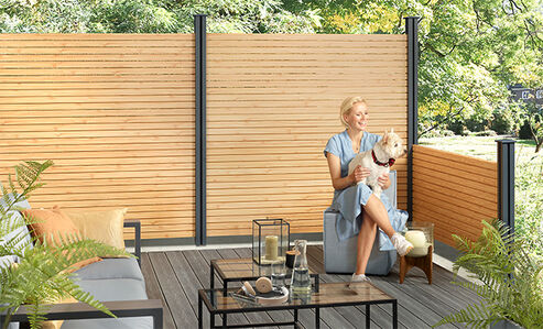 Woman and dog in the garden in front of Osmo privacy screen Alu-Fence Rhombus in Larche