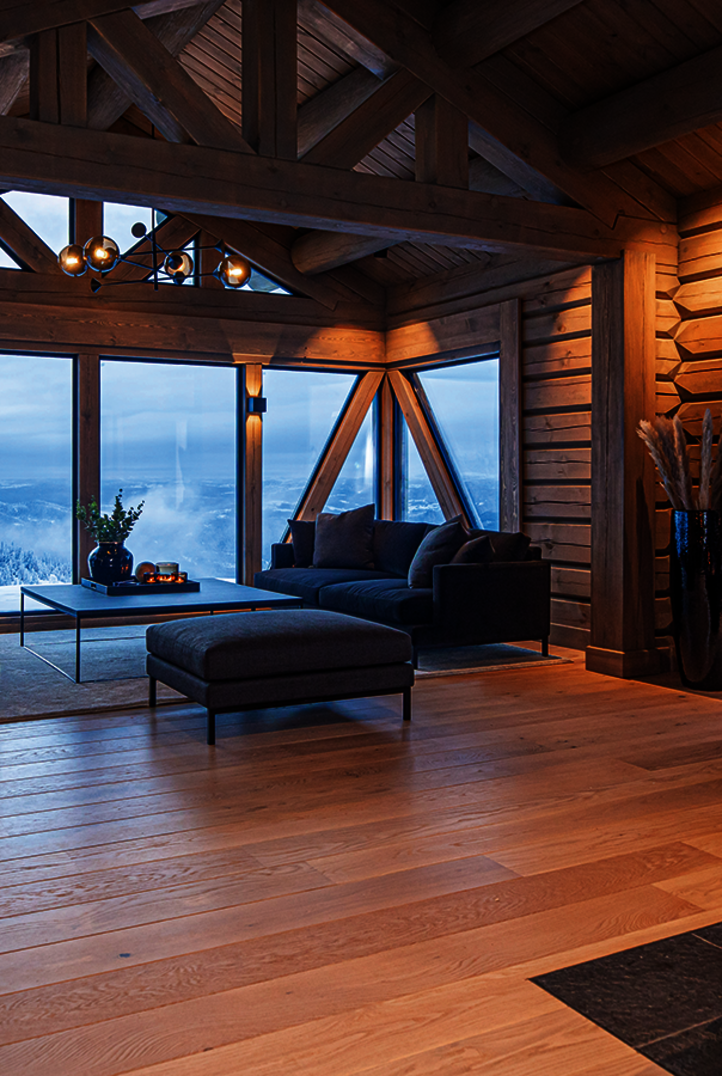 Modernes Wohnzimmer in einer Blockhütte mit Wänden und Balken aus mit graubraunem Osmo Dekorwachs behandeltem Holz