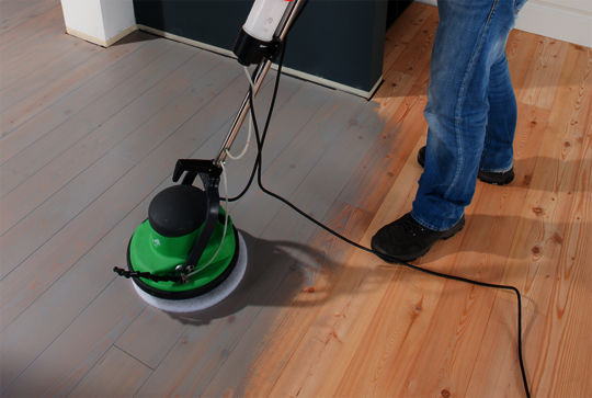 Using Osmo FloorXcenter, buff Dekorwachs into the wooden floor with a white pad and spread the remaining coating