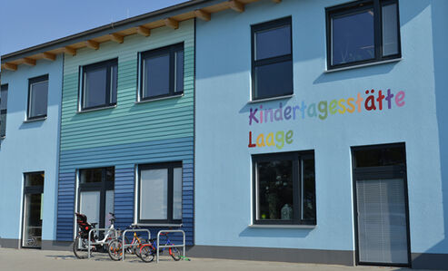 Osmo Referenz – Auf den blauen Gebäuden der Kindertagesstätte kommt die Fassade aus Lärchenholz in Blautönen gut zur Geltung