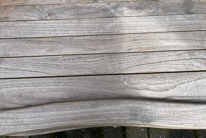 Vergraute Oberfläche einer Holzbank im Garten