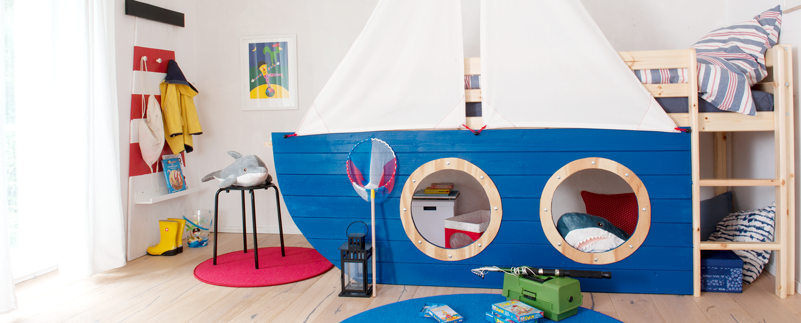 Kinderzimmer im maritimen Stil mit Segelboot-Hochbett und Leuchtturm-Garderobe