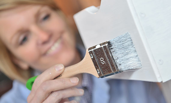 Osmo Farbe und Anstriche - Frau streicht Holzmöbel an OSMO
